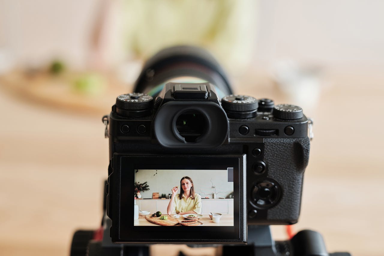 testimonials-img Caucasian woman vlogging at home with camera in a kitchen setting, captured indoors.