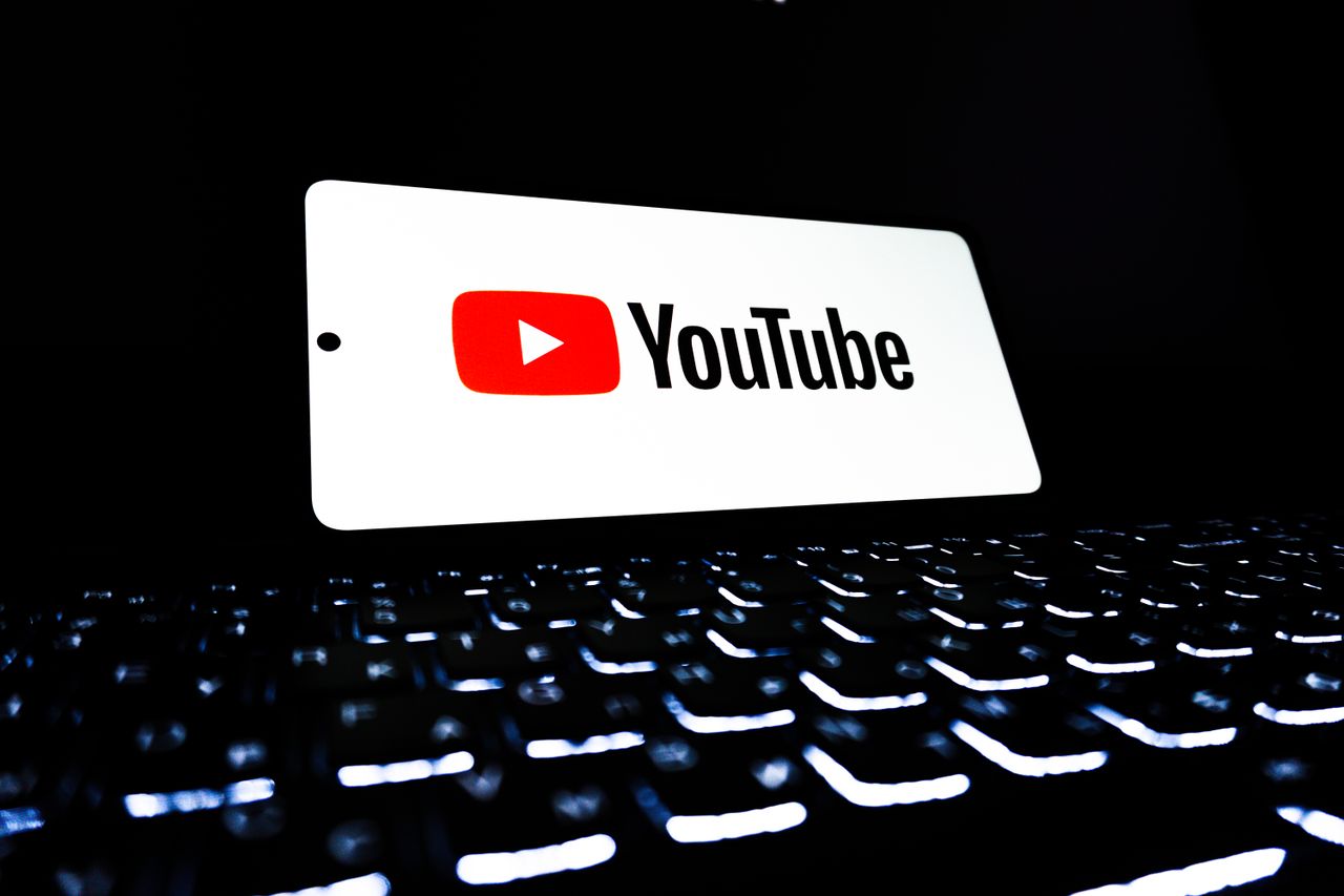 home-services-01 YouTube app icon displayed on a smartphone over an illuminated keyboard, representing digital media and online streaming.